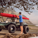 A photo of someone strapping a sea kayak to the roof of a dune buggy.